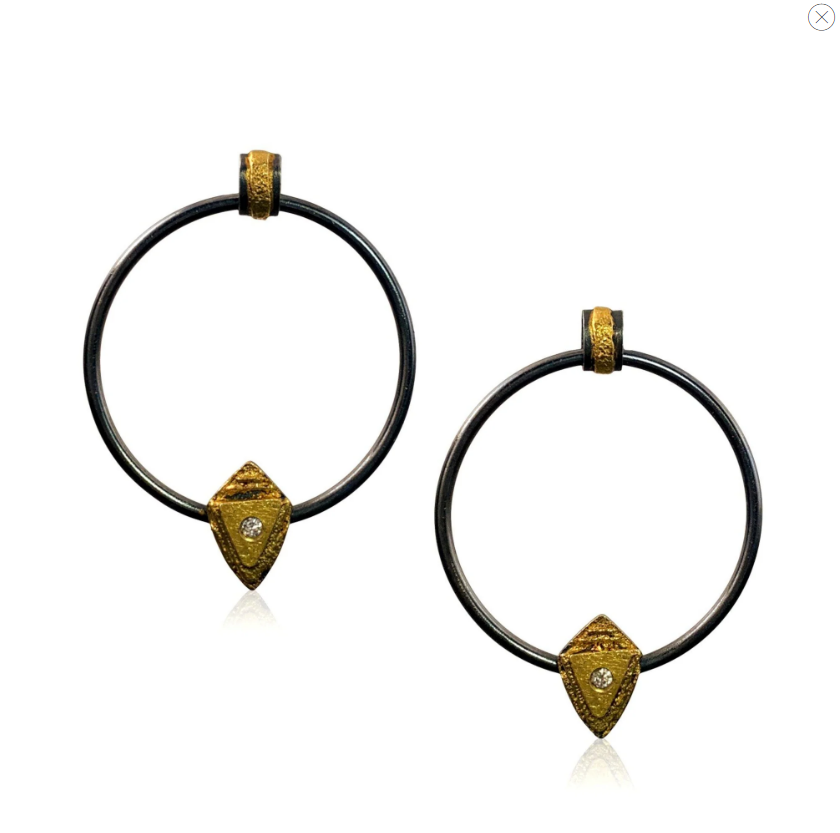 Front view of two earrings. Each is a big, dark gray hoop. At the top of each hoop is a dark gray and textured yellow gold piece that holds the post. At the bottom is a textured yellow gold shield shape with a small diamond in the center.