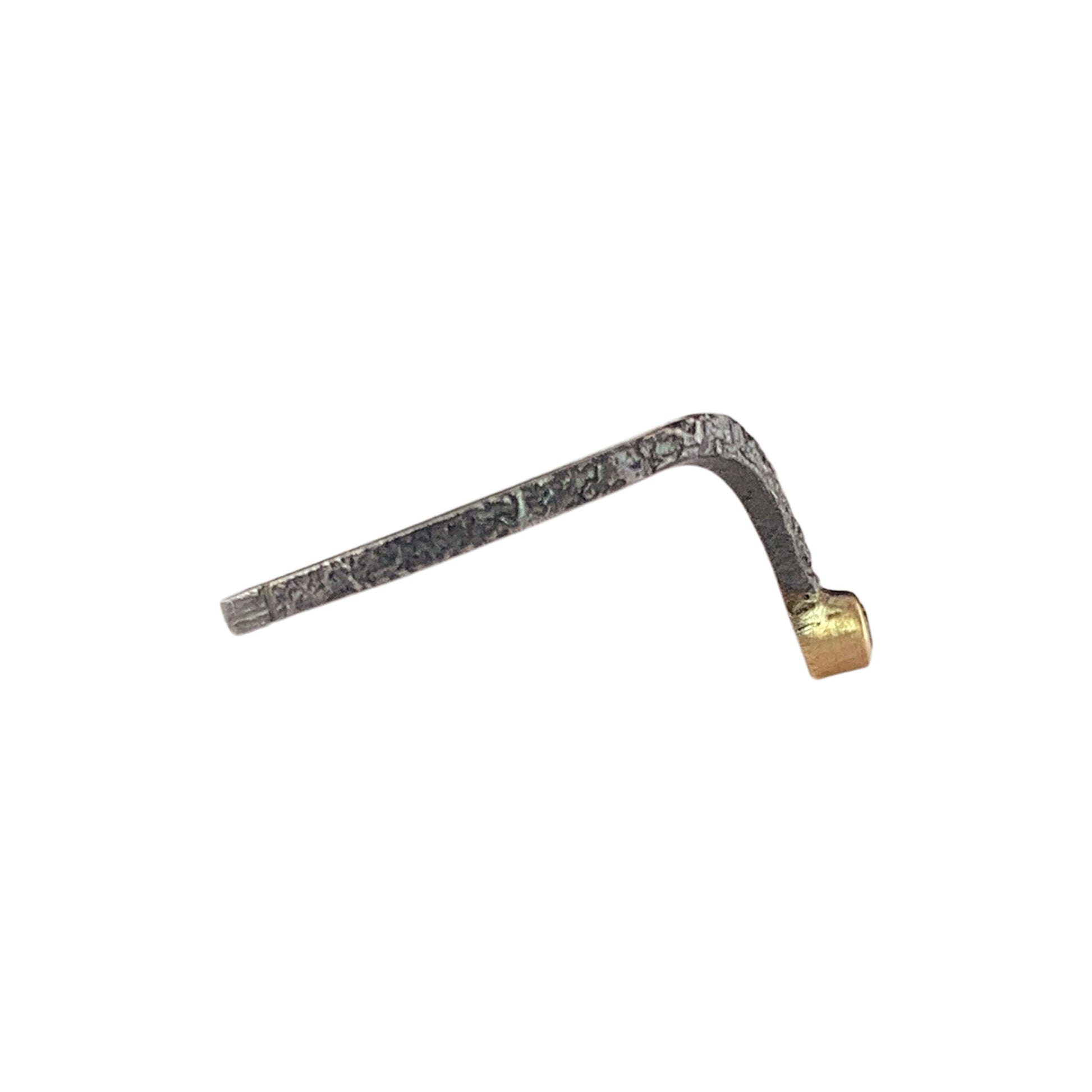 Side view of a textured dark gray band that dips down to a V on the right. At the end of the V is smooth yellow gold, which holds a diamond (not visible).
