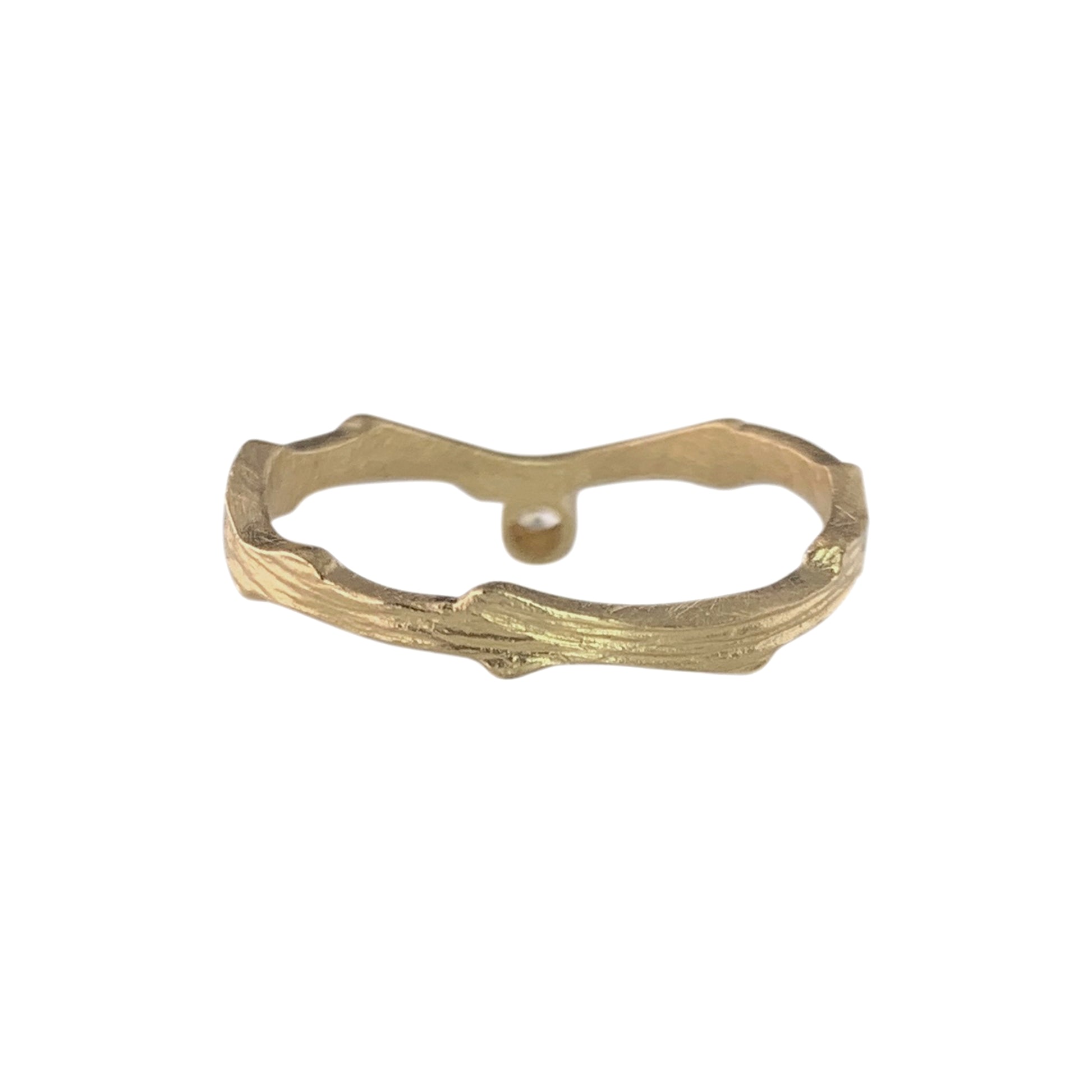 Back view of a gold ring with a wavy, textured band. On the far side of the band is a gold disc that holds an almost flush diamond on the other side.
